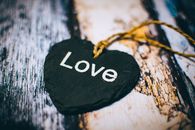 Close-up of a heart-shaped slate inscribed with 'Love' on a rustic wooden background, ideal for Valentine's themes.